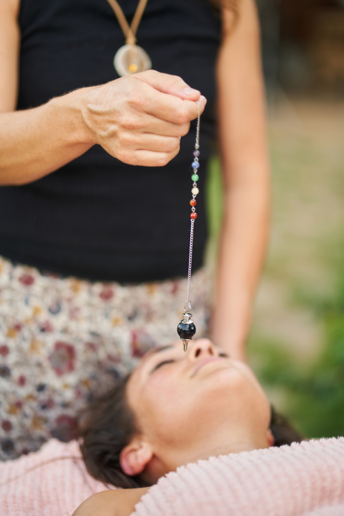 Cropped unrecognizable careful masseuse doing stone massage for woman with eyes closed while preparing for aromatherapy in summer garden