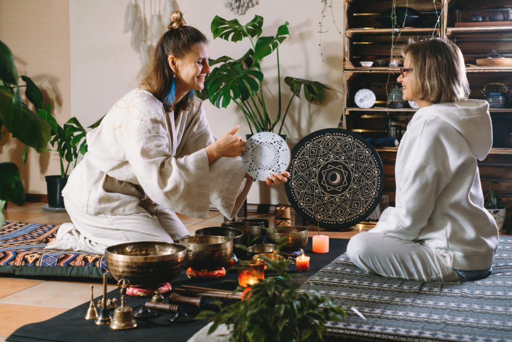 Sound healing with singing bowls, vibration massage and alternative therapy. Mental health care in green atmospheric studio. Woman playing to percussion instrument. singing along, meditating music