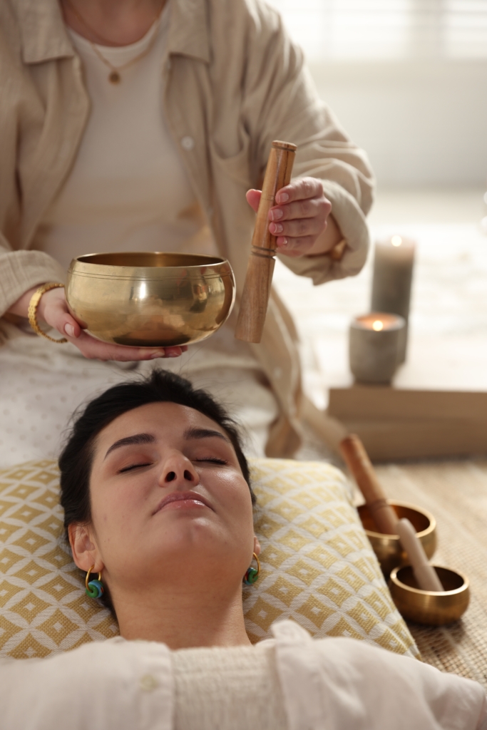 Woman undergoing singing bowl therapy lying on floor indoors