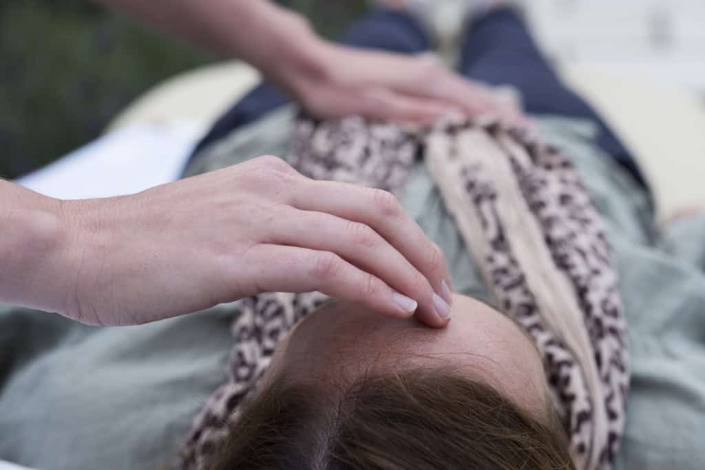 Woman on a couch and a therapist touching her head and stomach